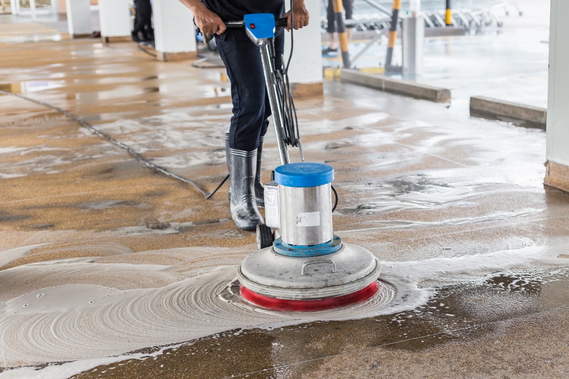 Cleaner running a floor machine across a construction-site walkway